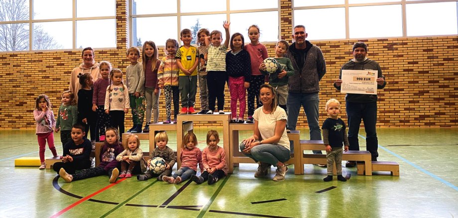 Die Kinder-Turngruppe mit den Übungsleiterinnen Christina Scholzen (v.) und Sarah Groß (hl) bei der symbolischen Scheckübergabe an den TuS DJK Dreiborn, vertreten durch Wilfried Ronig (h v.r.) und Ronny Berners.