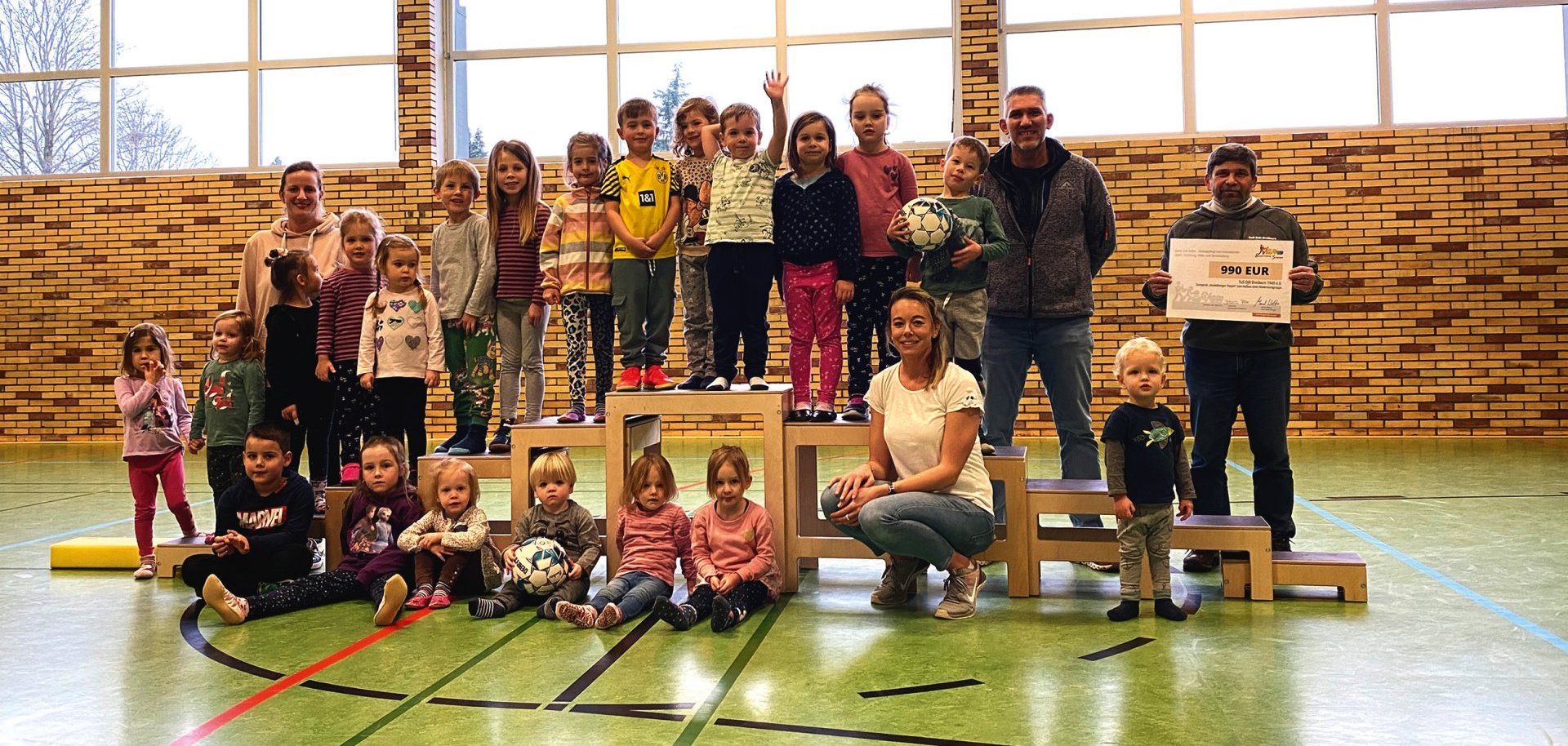 Die Kinder-Turngruppe mit den Übungsleiterinnen Christina Scholzen (v.) und Sarah Groß (hl) bei der symbolischen Scheckübergabe an den TuS DJK Dreiborn, vertreten durch Wilfried Ronig (h v.r.) und Ronny Berners.
