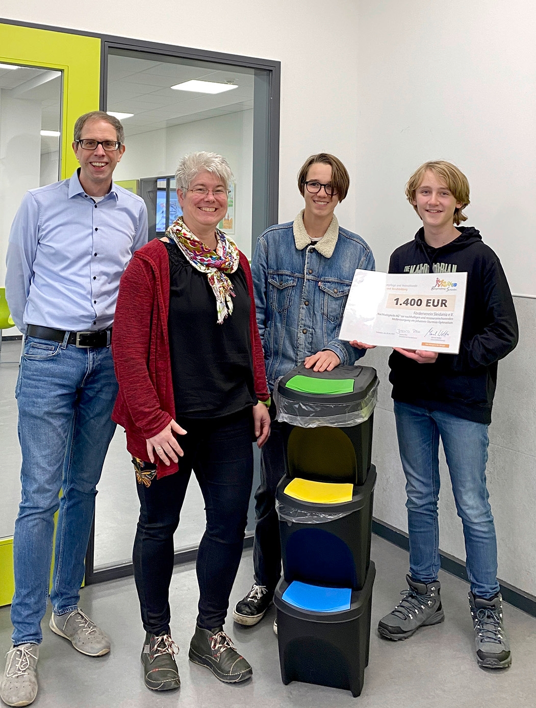 Freuen sich über die neuen Müll-Trennsysteme  in den Klassenräumen: v.l. Stefan Marenbach  (Stellvertretender Schulleiter), Marion  Lenzen (Kassiererin Förderverein Sleidania),  Jona Bastgen und Hlynur Jakob Limbeck (AG  für Nachhaltigkeit).