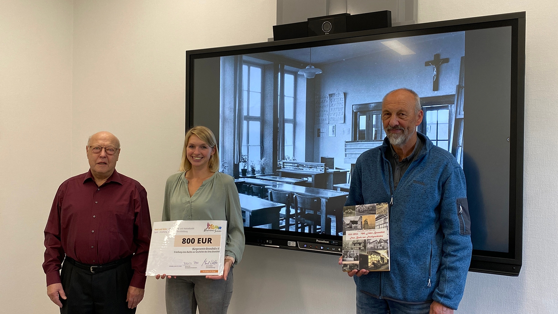 Martina Wassong, 1. Vorsitzende des Bürgervereins Bronsfeld (m.) nahm gemeinsam mit Artur Stoff (l.), der die Chronik mit Frajp Erben-Floeth (r.) gestaltete, den Förderscheck der Bürgerstiftung im Schleidener Rathaus entgegen.