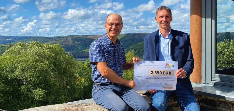 Symbolische Scheckübergabe vor der herrlichen Kulisse des Urftsees: Georg Toporowsky, Pastoralreferent im Nationalpark Eifel (l) und Marcel Wolter, Geschäftsführer der Bürgerstiftung Schleiden.
