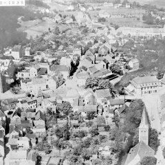 Diese Luftaufnahme mit St. Nikolaus links und Trinitatiskirche (unten rechts) stammt aus dem Jahre 1932, in Verlängerung der Blickachse von der evangelischen Kirche (Bahnhofstraße) auf das Hotel Friedrichs, das von 1811 stammte und vor Aufkommen des Fremdenverkehrs nach 1880 vornehmlich Kaufleute, Beamte und Offiziere beherbergte. Im Gästebuch finden sich unter anderem Zeichnungen der Eifelmaler Fritz von Wille und Ernst Inden. (Repro: SA Schleiden)