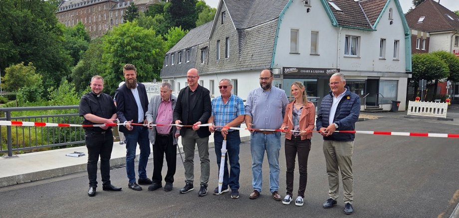 07/2025 - Bild 01: Pfarrer Thomas Schlütter, Sebastian Pelzer, Werner Kaspar, Bürgermeister Ingo Pfennings, Gerd Breuer, Daniel Lansch, Nadine Michels und Guido Fleischmann beim Durchschneiden des Einweihungsbandes. 