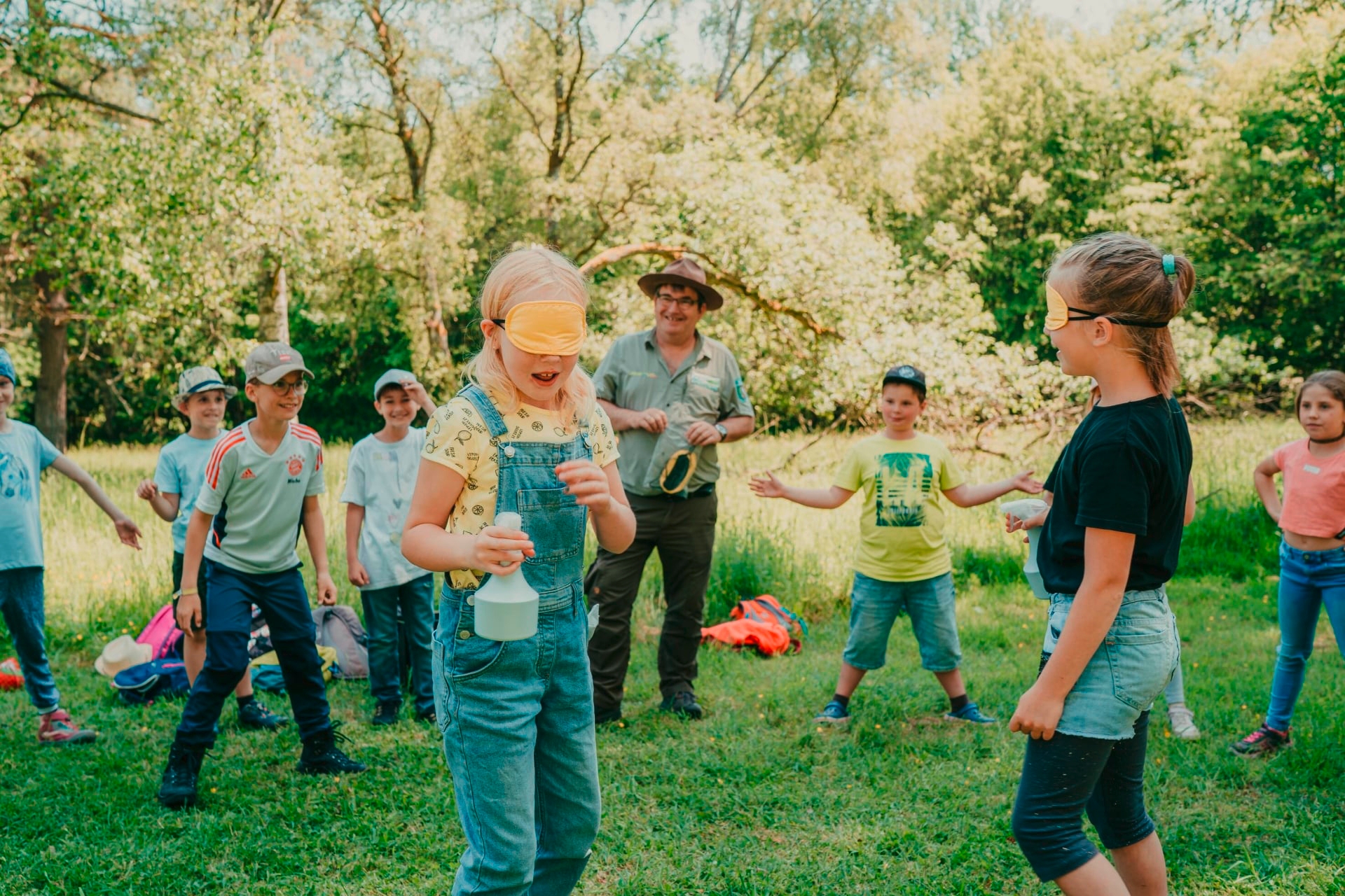 Mit den Sinnen einer Fledermaus auf Insektenjagd. Beim Fledermausspiel versuchen Kinder mit verbundenen Augen auf feinste Hörzeichen in ihrer Umgebung zu achten, um sich kein Nachtfalter – hier die umstehenden Kinder, - entgehen zu lassen.