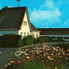 Fotosammlung H. Wollgarten und F.A. Heinen - Ansichtskarte um 1970: 1926 wurde das neue Schulhaus („Schöll“, „Schu-el“) in der Weinhardstraße errichtet und in den 1960er Jahre erweitert. Heute dient die Schule als Bürgerhaus („Bürjehuus“) und Kindergarten („Köngdejaade“), die Gymnastikwiese als Spielplatz.