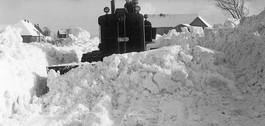 Ein belgischer Caterpillar des Camps Vogelsang räumt den Schnee von der Straße.