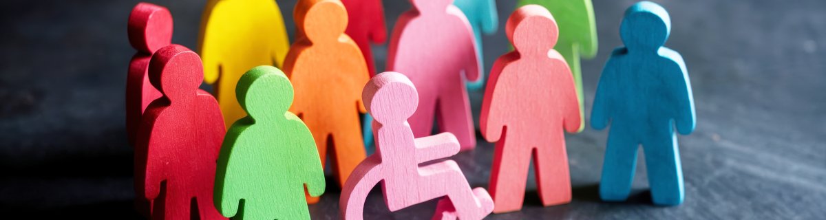 Bunte Gruppe von hölzernen Menschenfiguren unterschiedlicher Farbe, darunter Rollstuhlfahrer.