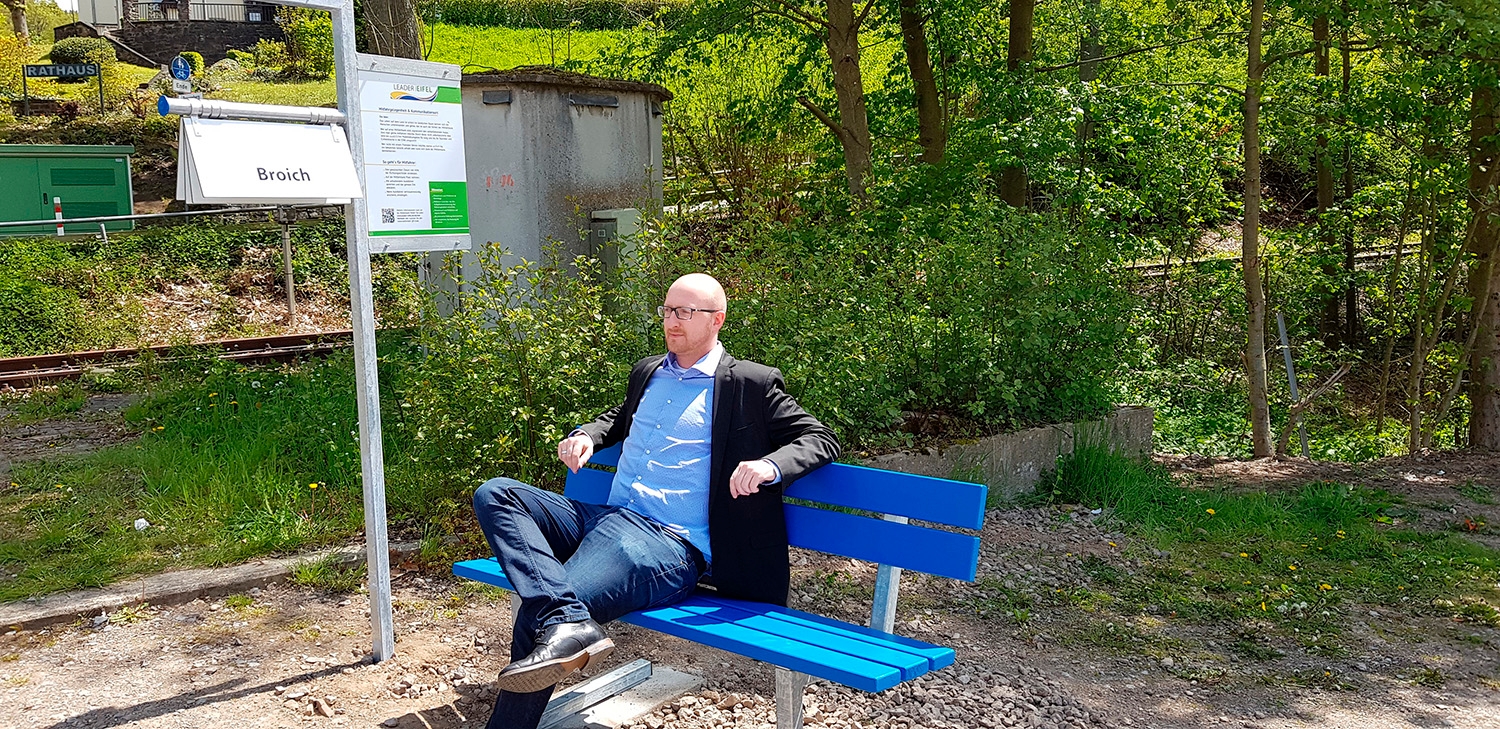 Bürgermeister Pfennings hat auf der Mitfahrbank unterhalb des Rathauses Platz genommen.