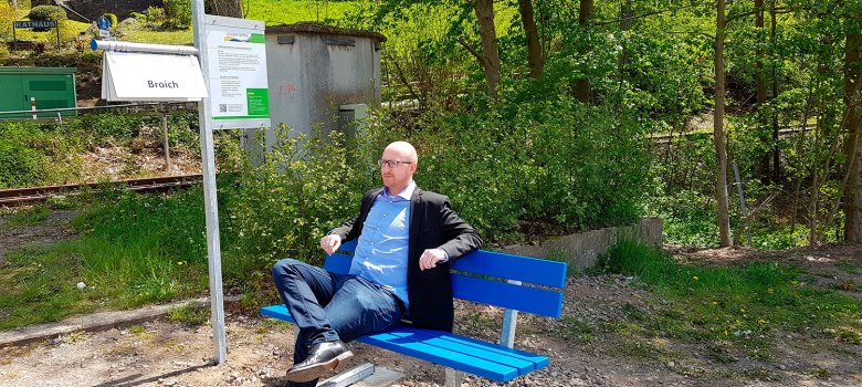 Bürgermeister Pfennings hat auf der Mitfahrbank unterhalb des Rathauses Platz genommen. Mitfahrbänke